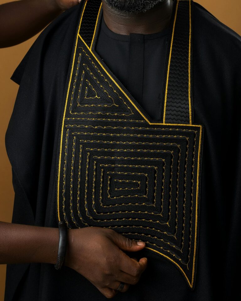 Close-up of traditional black attire with yellow embroidery in Kumasi, Ghana.